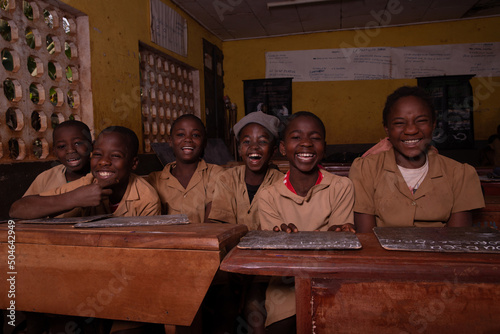 A group of six african pupils sitting at school desks with their blackboards