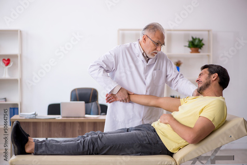 Young male patient visiting old male doctor chiropractor
