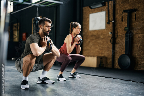 Photo Athletic couple doing kettlebell goblet squat exercise during cross training in gym