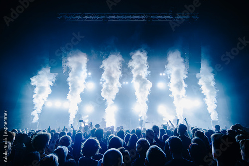 Co2 flame and silhouette of crowd at a music festival 
in front of bright stage lights