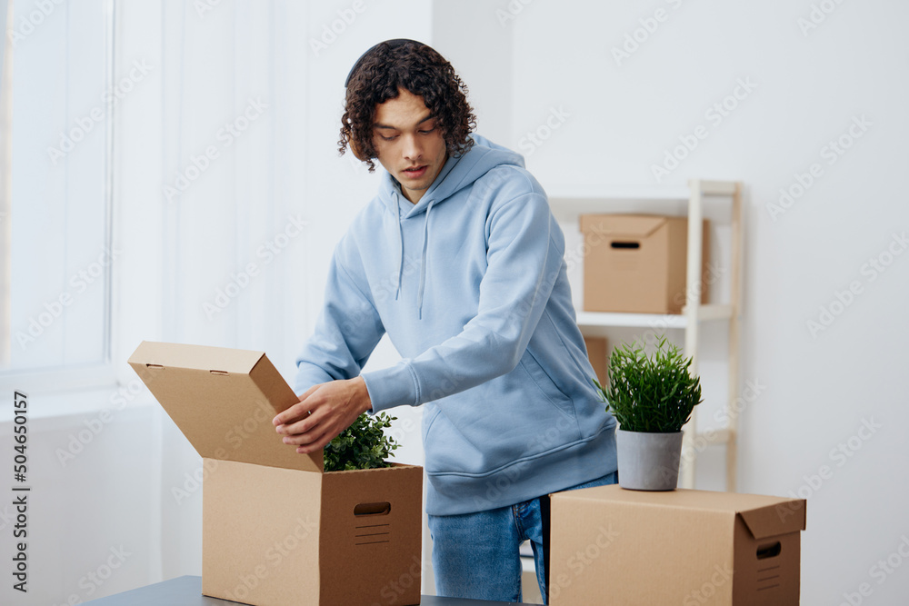 guy with curly hair unpacking things from boxes in the room sorting things out guy with curly hair unpacking things from boxes in the room sorting things out