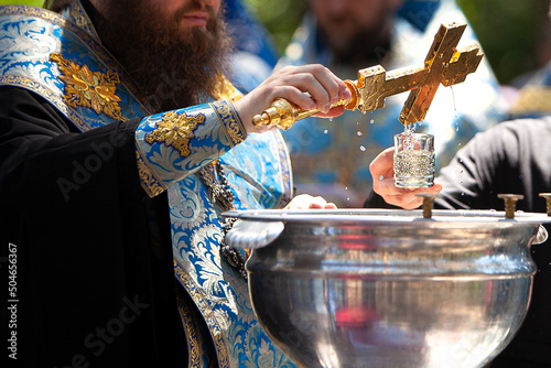 Orthodox priest blesses water with a cross