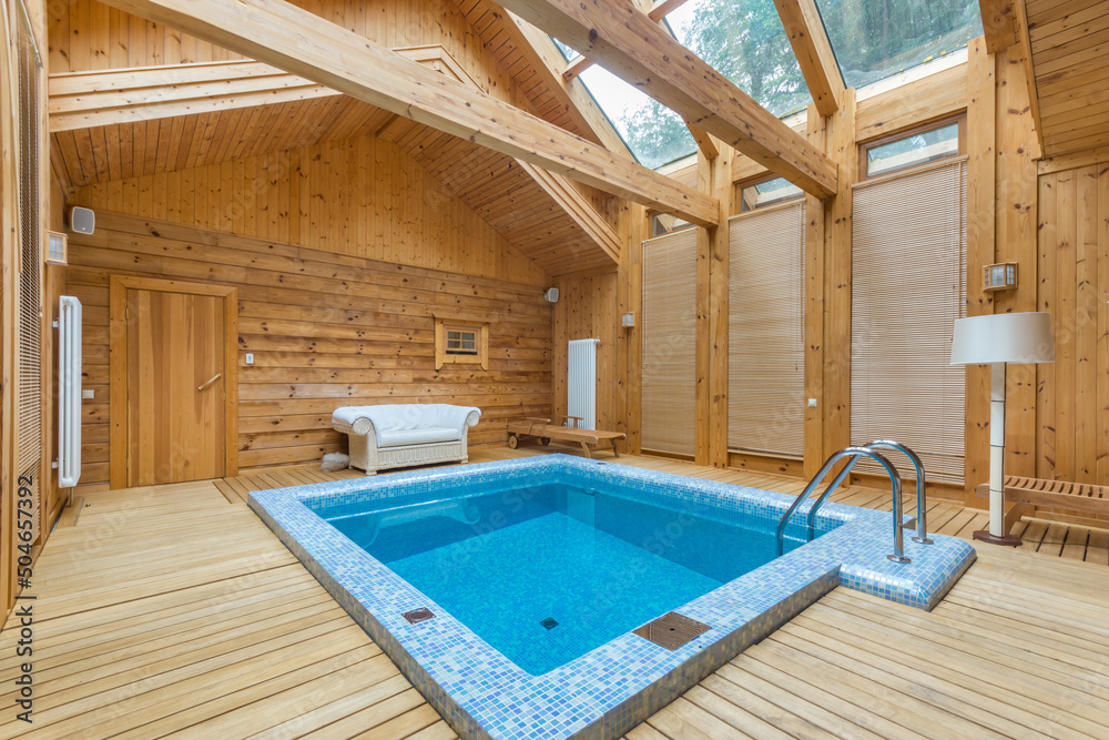 The room of a wooden house with windows on the roof and a swimming pool decorated with mosaic blue tiles. The room of a wooden house with windows on the roof and a swimming pool decorated with mosaic blue tiles.