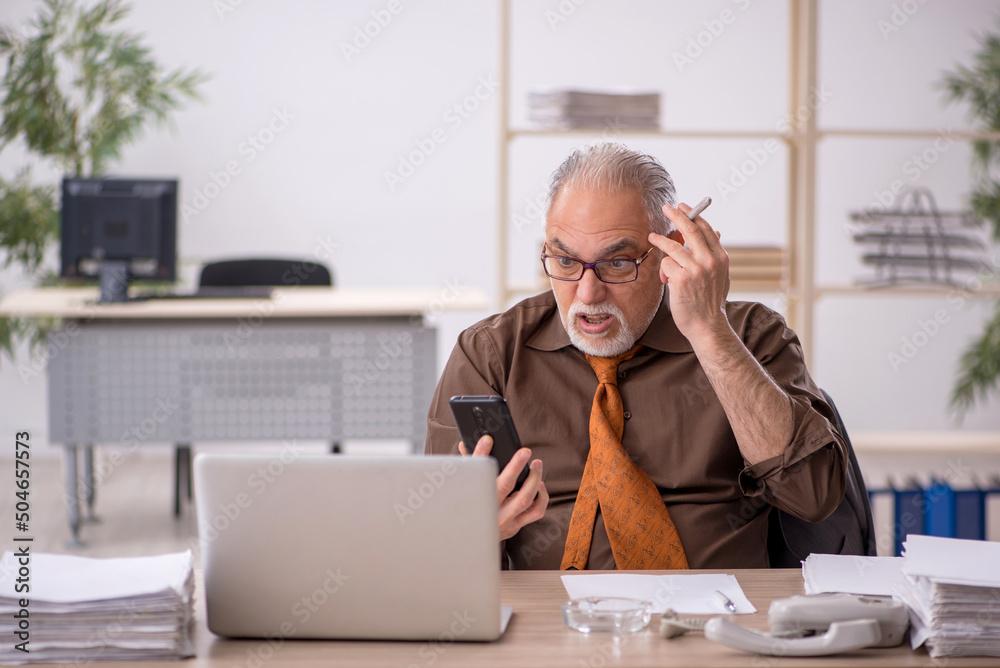 Old male employee smoking cigarette at workplace Old male employee smoking cigarette at workplace