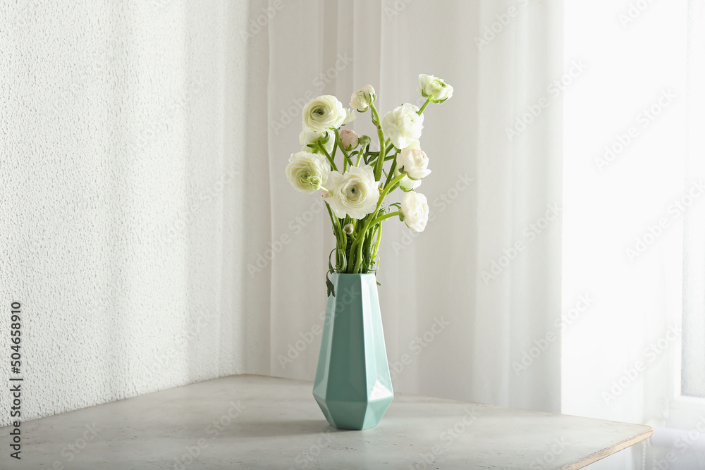 Vase with bouquet of beautiful ranunculus flowers on table