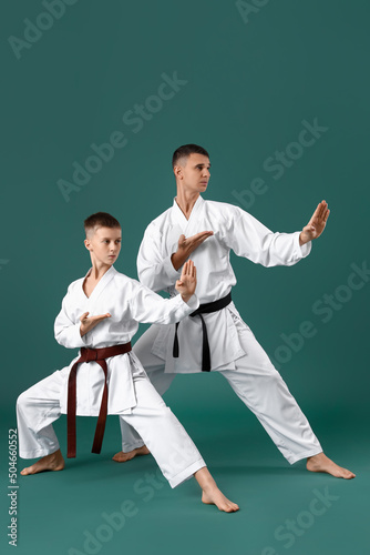 Boy practicing karate with instructor on green background photo