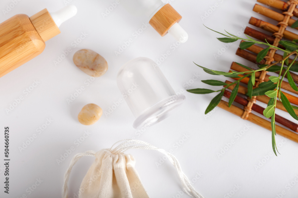 Vacuum jar for anti-cellulite massage and bottles of essential oil on white background