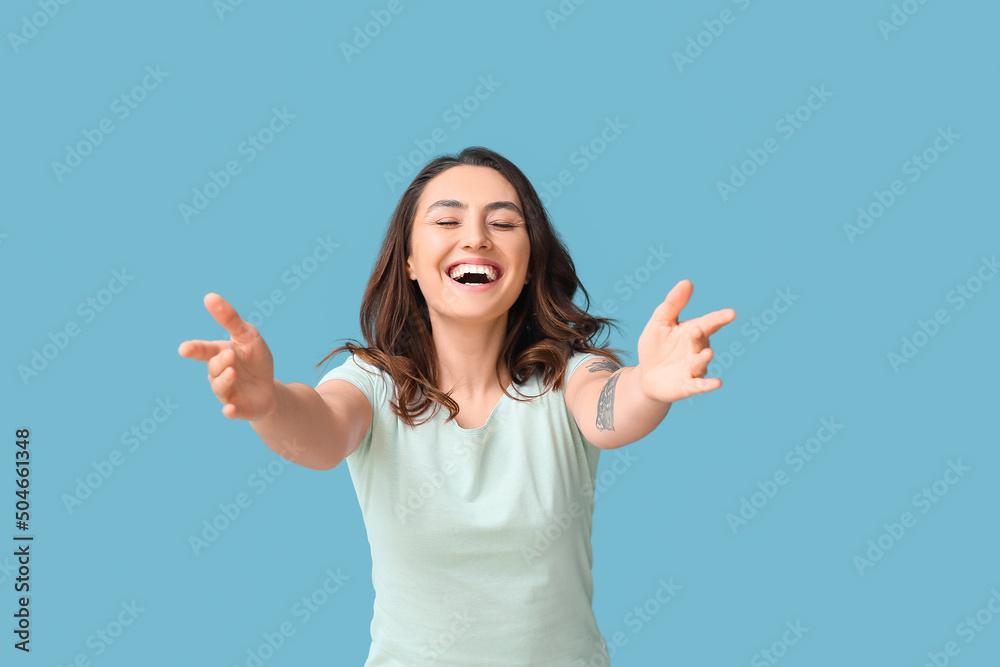 Happy young woman opening arms for hug on color background
