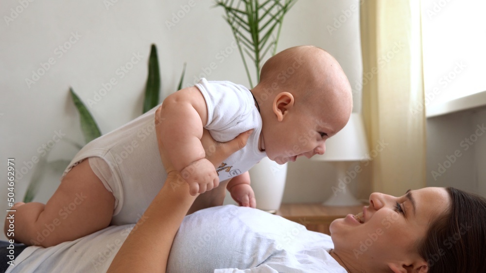 Authentic Young Caucasian Woman Holding Newborn Baby. Mom And Child On Bed. Close-up Portrait of Smiling Family With Infant On Hands. Happy Marriage Couple On Background. Childhood, Parenthood Concept