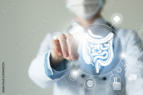 Unrecognizable female doctor holding graphic virtual visualization model of Intestine organ in hands. Multiple virtual medical icons.