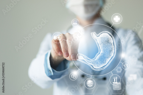 Unrecognizable female doctor holding graphic virtual visualization model of Stomach organ in hands. Multiple virtual medical icons. photo