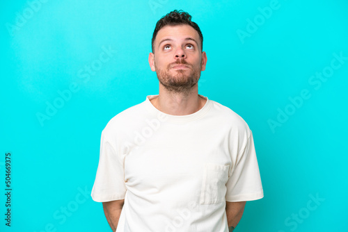 Young Brazilian man isolated on blue background and looking up