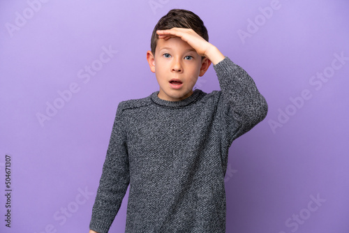 Little boy isolated on purple background doing surprise gesture while looking front