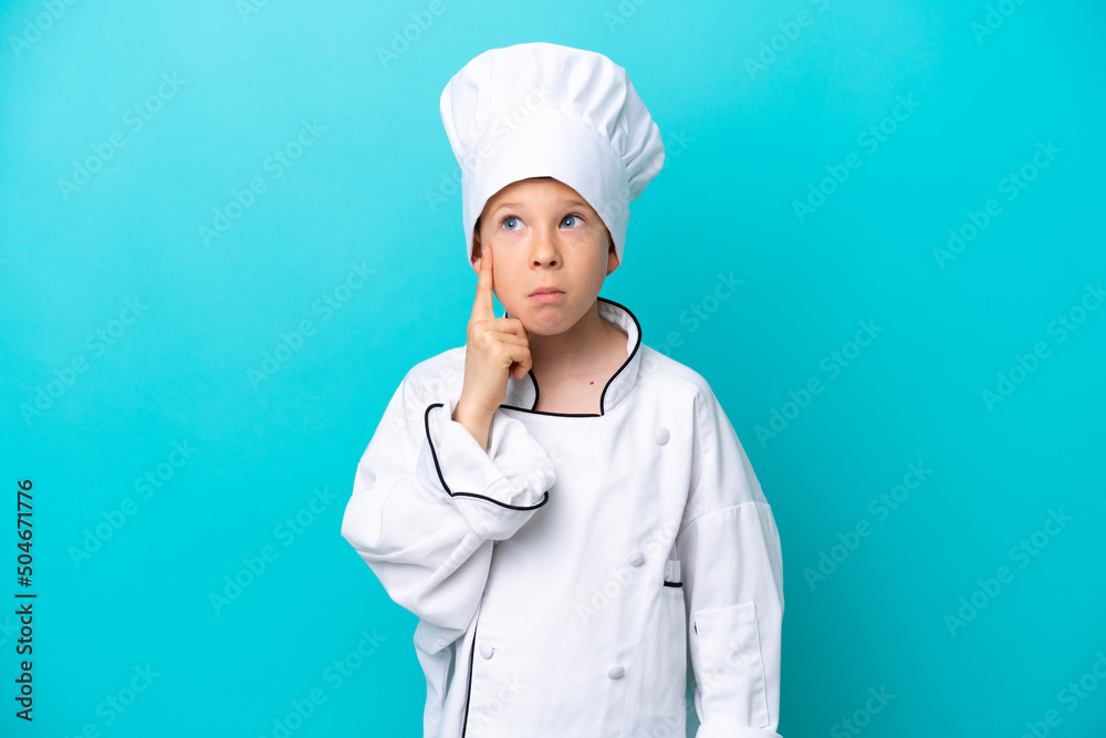 Little chef boy isolated on blue background thinking an idea Little chef boy isolated on blue background thinking an idea