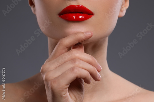 Young woman with beautiful red lips on grey background  closeup