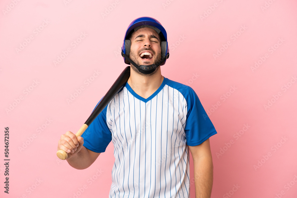 Baseball player with helmet and bat isolated on pink background laughing Baseball player with helmet and bat isolated on pink background laughing