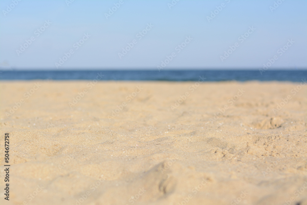 Blurred view of sandy beach near sea on sunny day Blurred view of sandy beach near sea on sunny day