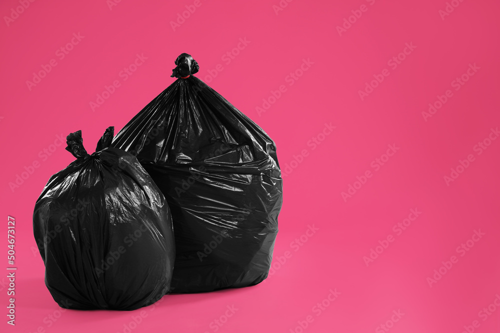 Trash bags full of garbage on pink background. Space for text
