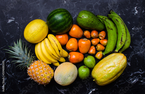 An enticing array of tropical fruits, including melons, pineapples, bananas, pixbaes, lulos, guavas, and plantains, bursting with vibrant colors and flavors. photo