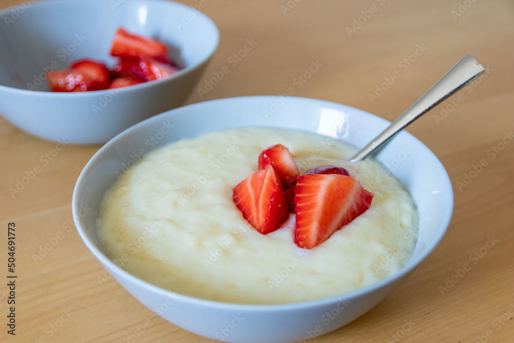 Many cut strawberries with rice pudding in bowl are ready to eat with silver spoon or as delicious finger food and healthy snack with red fruit and vitamins on wooden kitchen table for sustainable nut Many cut strawberries with rice pudding in bowl are ready to eat with silver spoon or as delicious finger food and healthy snack with red fruit and vitamins on wooden kitchen table for sustainable nut