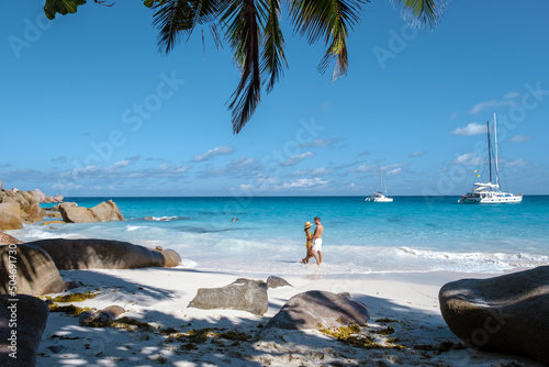 Anse Georgette Praslin Seychelles, young couple of men and woman on a tropical beach during a luxury vacation in Seychelles. Tropical beach Anse Georgette Praslin Seychelles.