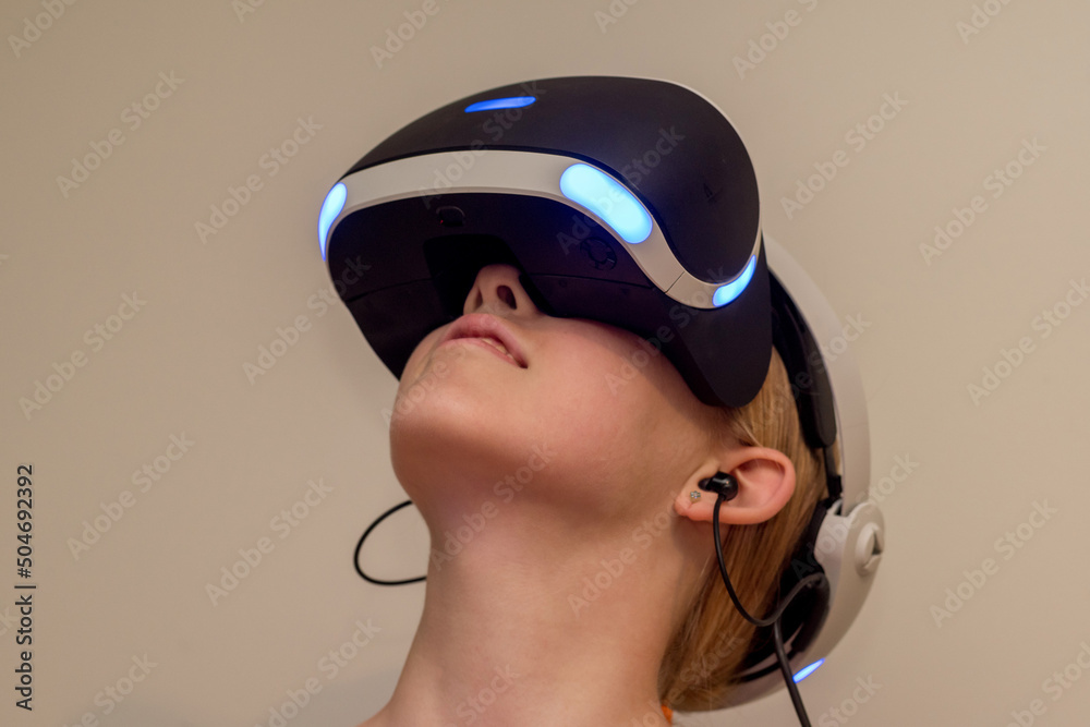 A teenage girl wearing VR glasses headset . Virtual reality simulator technology. Gaming A teenage girl wearing VR glasses headset . Virtual reality simulator technology. Gaming