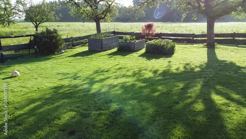 drone flight through stylish garden with vegetable bed surrounded by green fresh lawn and trees 