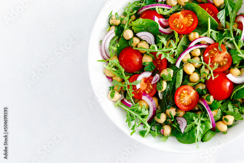 Vegetarian chickpea salad with tomatoes, arugula, parsley, spinach and red onion. Healthy food, diet. Top view
