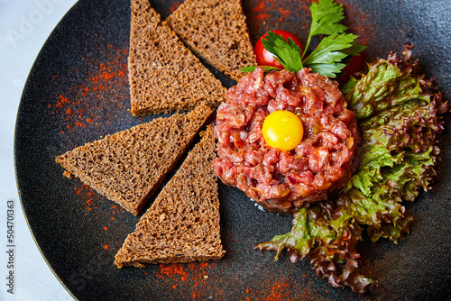Fotografie Veal tartare with egg and toasts on a plate in a restaurant