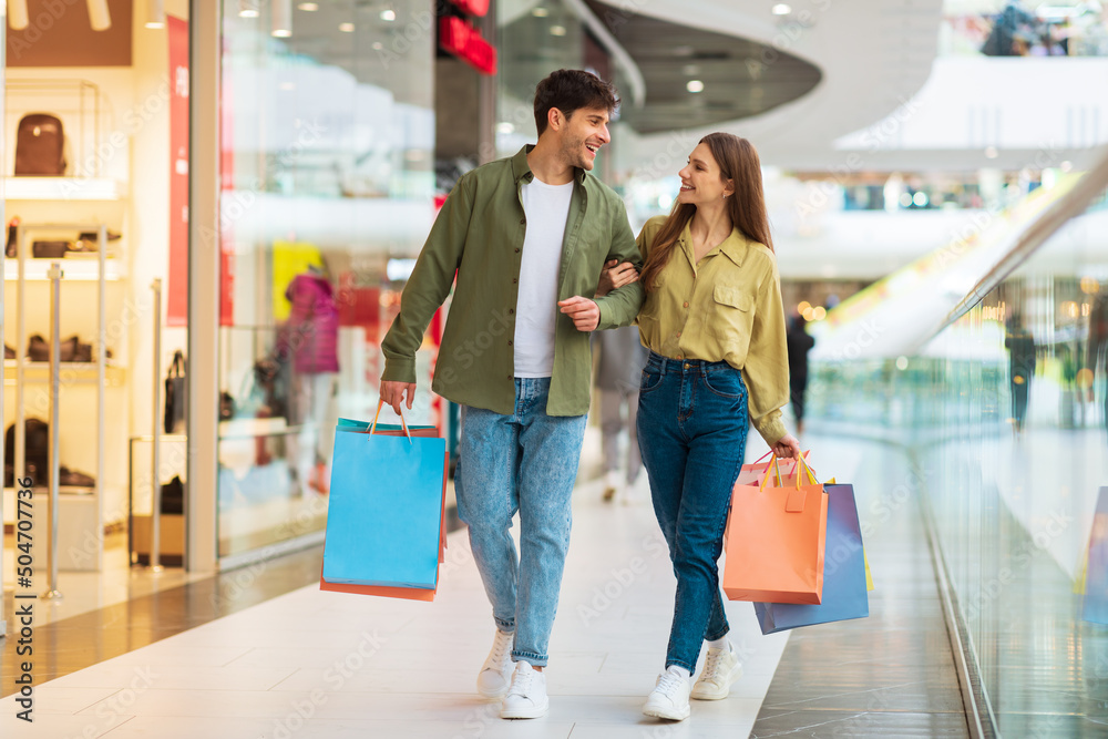 Cheerful Couple Shopping Walking Carrying Shopper Bags In Mall Cheerful Couple Shopping Walking Carrying Shopper Bags In Mall