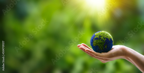 Hands holding globe on green nature forest background in saving environment concept, save clean planet, ecology concept for World Earth Day