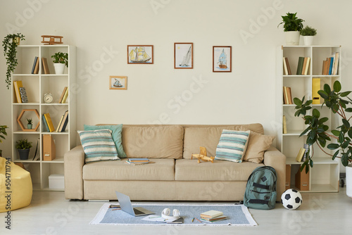 Interior of cozy living room with kids stuff and ship pictures above sofa, house design concept © Mediaphotos