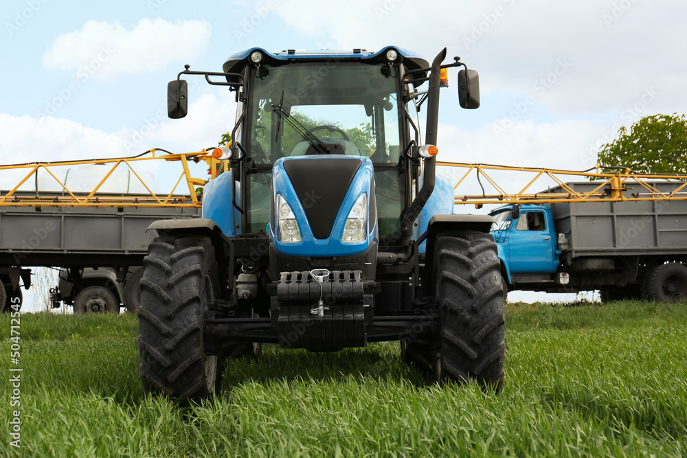 Fototapeta premium Modern tractor and truck in field on sunny day. Agricultural industry