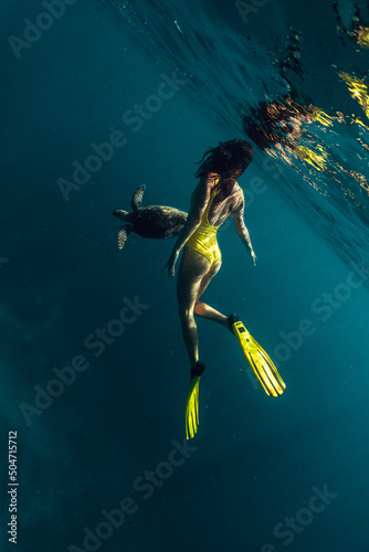 snorkeling Freediver woman and turtle in natural habitat. underwater contact of Beautiful girl swim next to wild animals on surface of clear blue sea or ocean. Unique sea voyage, trip, travel.