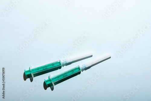 A pair of medical syringes on blue background with free copy paste space for text.