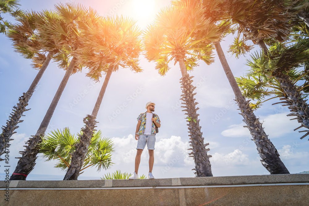 Young traveler man at summer holiday vacation with beautiful palms and seascapes at background