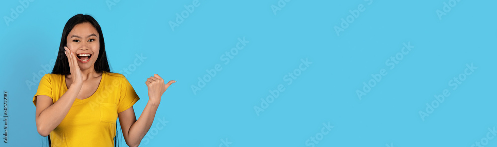 Happy surprised millennial japanese woman in yellow t-shirt with open mouth pointing finger at empty space Happy surprised millennial japanese woman in yellow t-shirt with open mouth pointing finger at empty space