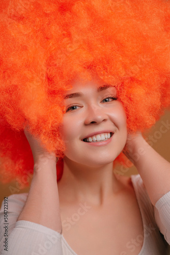 Smiling young orange haired woman on beige background. Close up portrait. photo