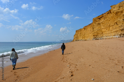 Two women walking on Hive Beach, Jurassic Coast, Dorset, UK photo