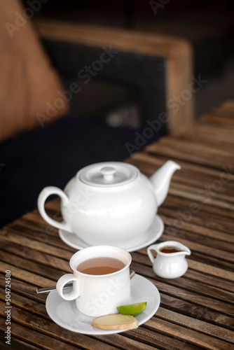 ginger and honey tea pot and cup on wooden cafe table outdoors