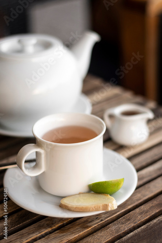 ginger and honey tea pot and cup on wooden cafe table outdoors