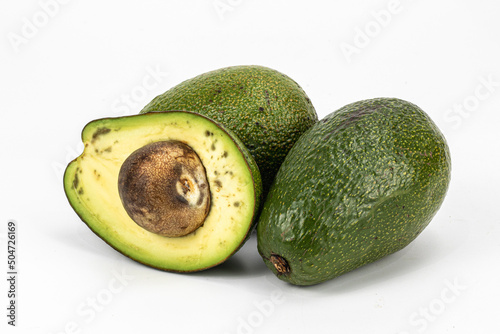 Hass avocado isolated in white background, decorated with wooden logs, macro shot using studio lighting photo