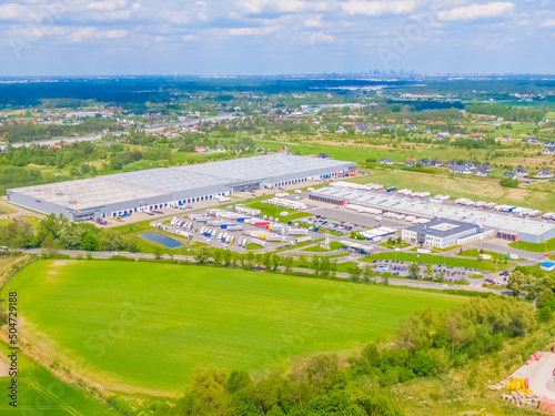 Aerial view of goods warehouse. Logistics center in industrial city zone from above. Aerial view of trucks loading at logistic center