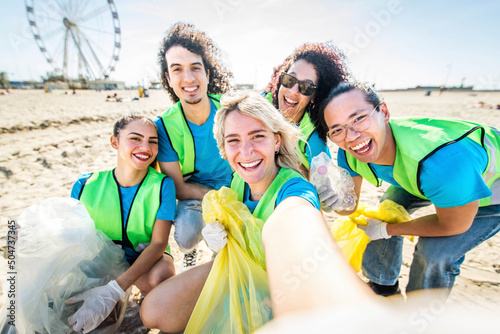 Group of eco volunteers picking up plastic trash on the beach - Activist people collecting garbage protecting the planet - Ocean pollution, environmental conservation and ecology concept photo