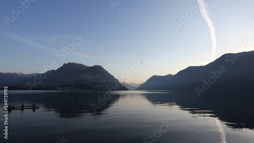 Sunrise at Lake Lugano in autumn winter with reflections on the water. Switzerland