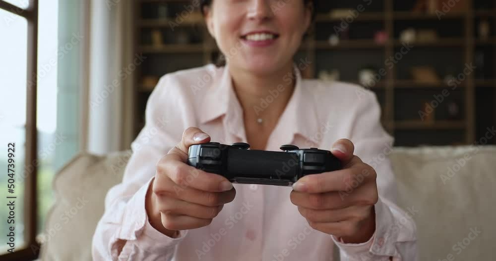 Smiling woman gamer relax alone on couch in living room using gamepad play video game, cropped close up view, single female engaged in digital virtual activity at home. Videogames addiction concept Smiling woman gamer relax alone on couch in living room using gamepad play video game, cropped close up view, single female engaged in digital virtual activity at home. Videogames addiction concept
