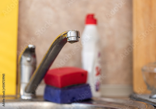 kitchen faucet on the background of the sink with sponges and detergent