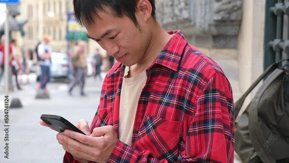 asian man holding smartphone in his hands scrolling screen with news or social media outdoor asian man holding smartphone in his hands scrolling screen with news or social media outdoor