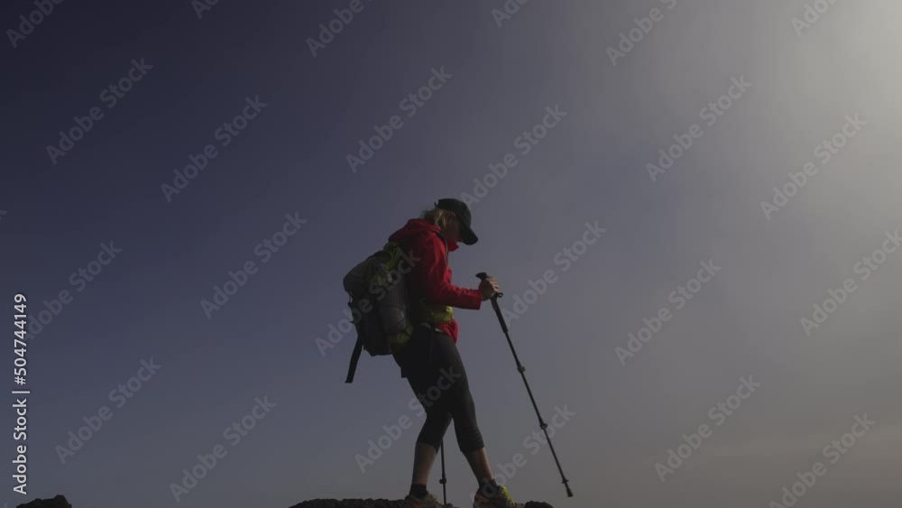 hiker walking on top of a mountain with a backpack and walking stiks hiker walking on top of a mountain with a backpack and walking stiks