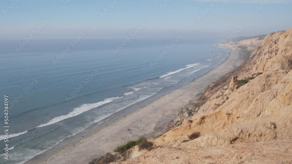 Steep cliff, rock or bluff, foggy weather, California coast erosion, USA. Eroded sandstone crag. Torrey Pines park vista, overlook viewpoint, ocean beach, waves from above. Seamless looped cinemagraph Steep cliff, rock or bluff, foggy weather, California coast erosion, USA. Eroded sandstone crag. Torrey Pines park vista, overlook viewpoint, ocean beach, waves from above. Seamless looped cinemagraph